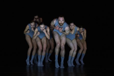 Promise - Theater St. Gallen Gruppentanz mit mehreren Tänzern in blauer Kleidung vor dunktem Hintergrund.