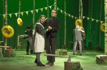 Tannöd - Theater Hof Zwei Personen tanzen im Wald, umgeben von Festdekoration und weiteren Personen im Hintergrund.