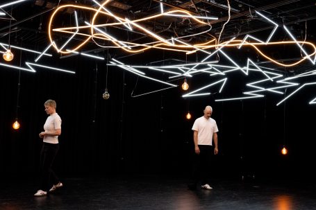 Konstellationen - Rheinisches Landestheater Neuss Zwei Tänzer in einem beleuchteten Raum mit geometrischen Lichtinstallationen.